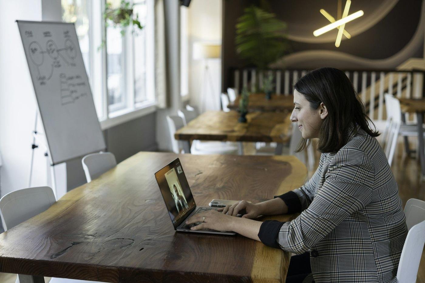 Woman on a video call using a laptop at a long table