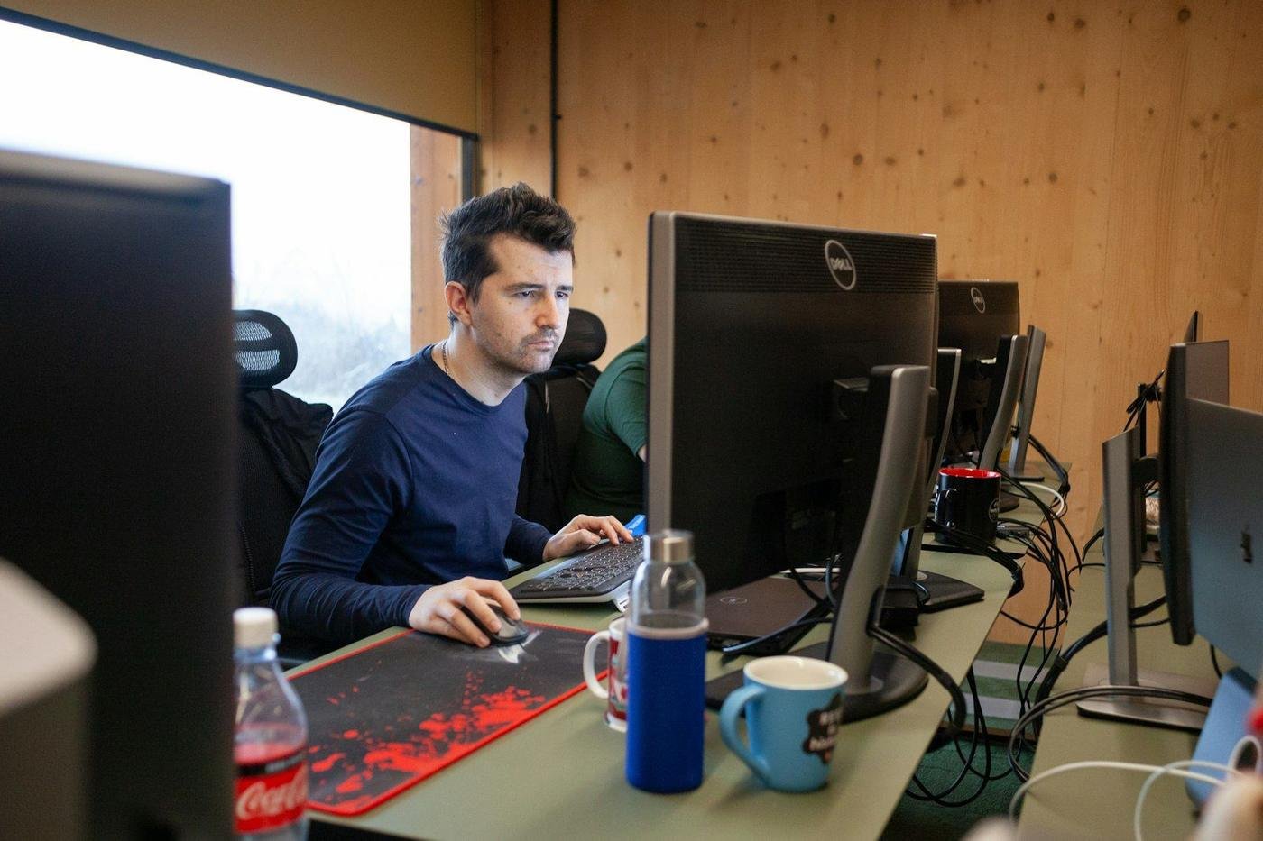Man working at a desk with multiple computer monitors