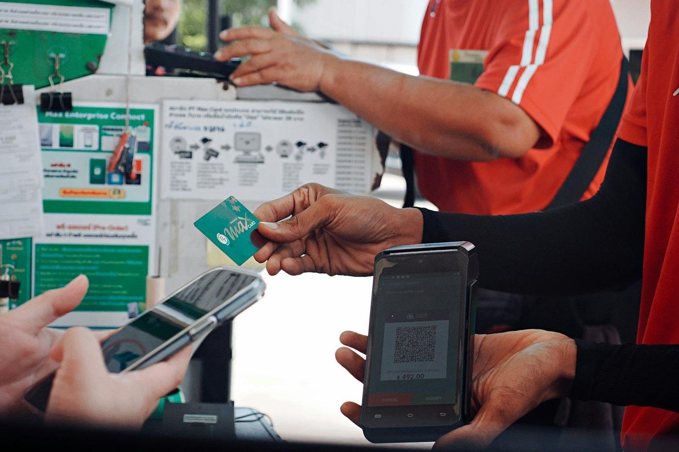 Customer paying with a smartphone and card at a checkout counter