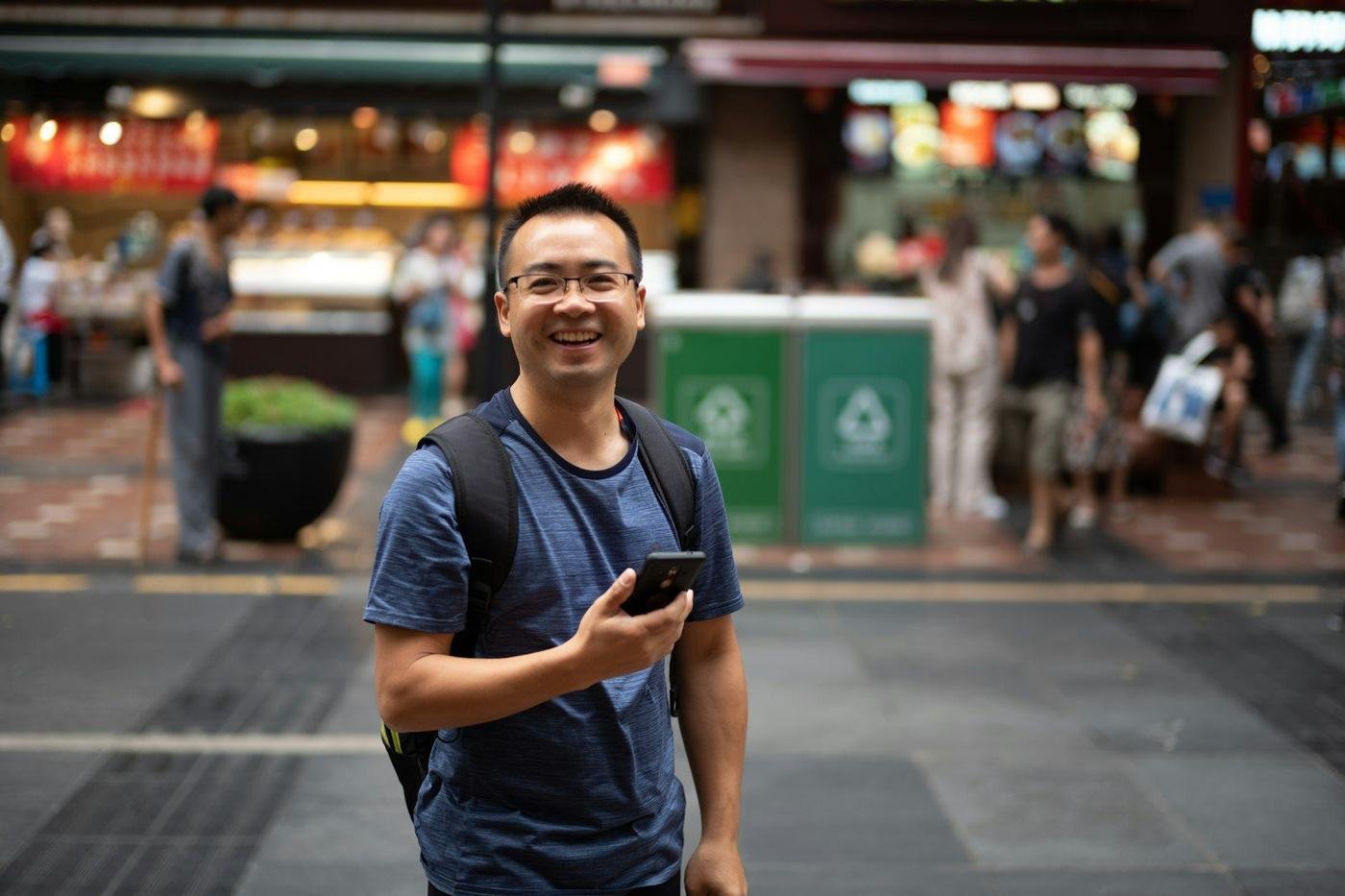 Smiling man holding a smartphone on a busy city street