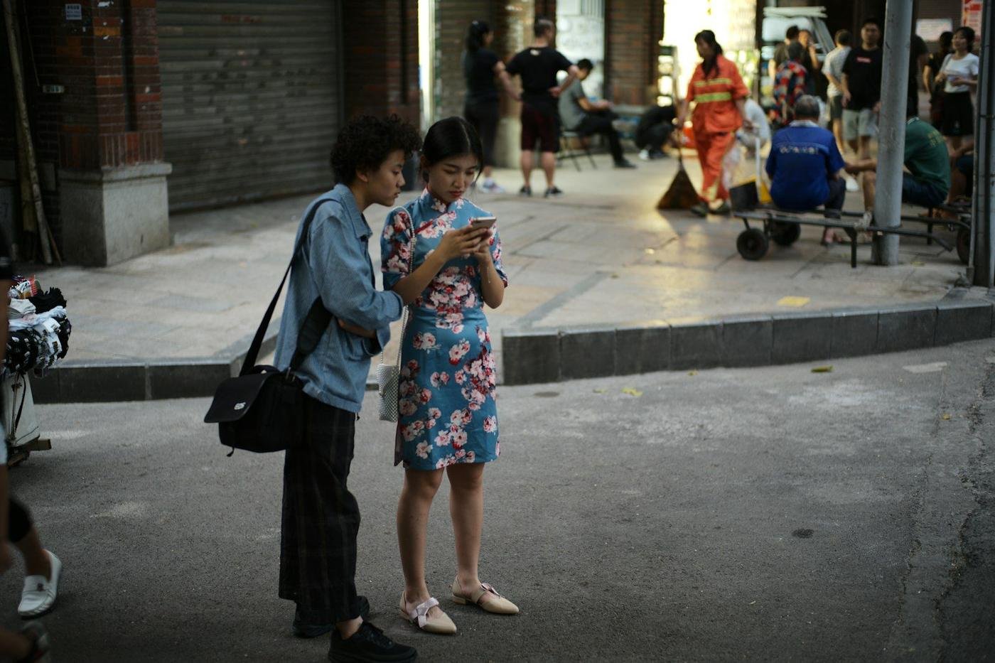 Two young women looking at a smartphone on a city street