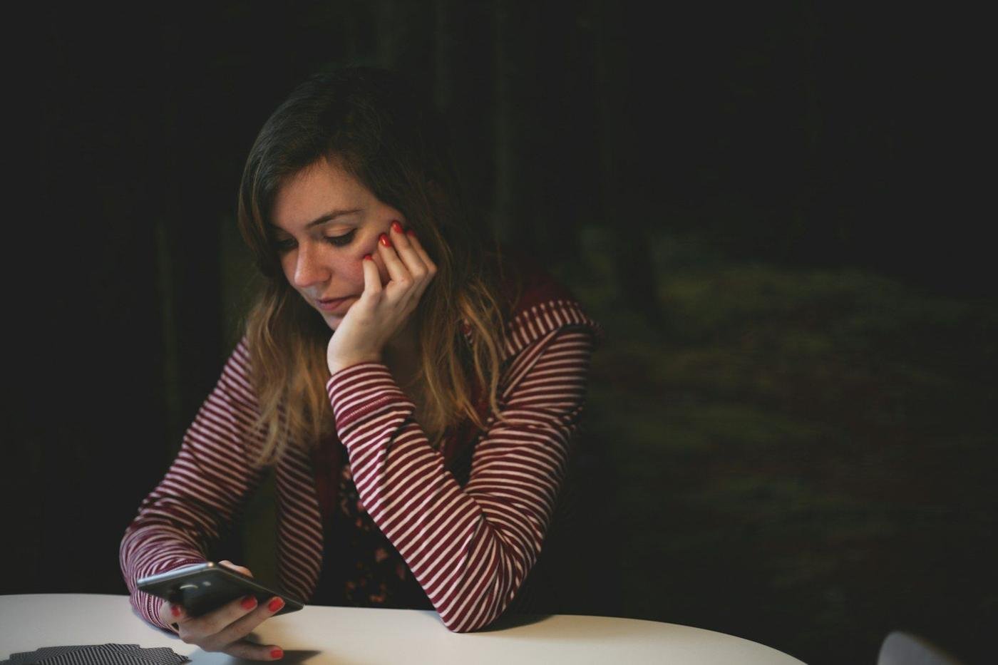 Woman resting her head on her hand while using a smartphone