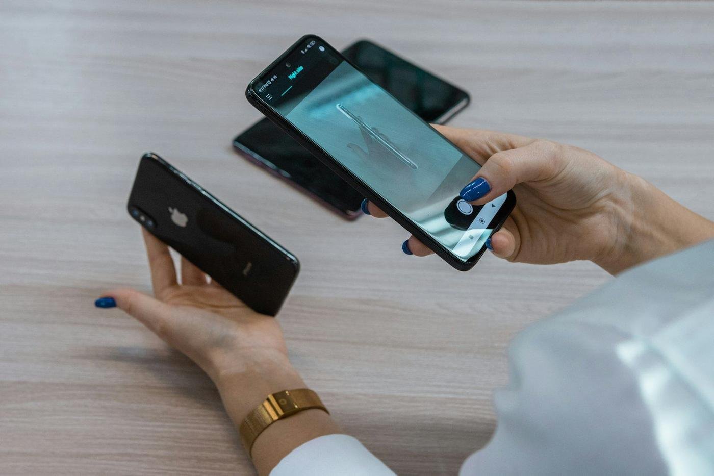Hands holding two smartphones over a wooden table