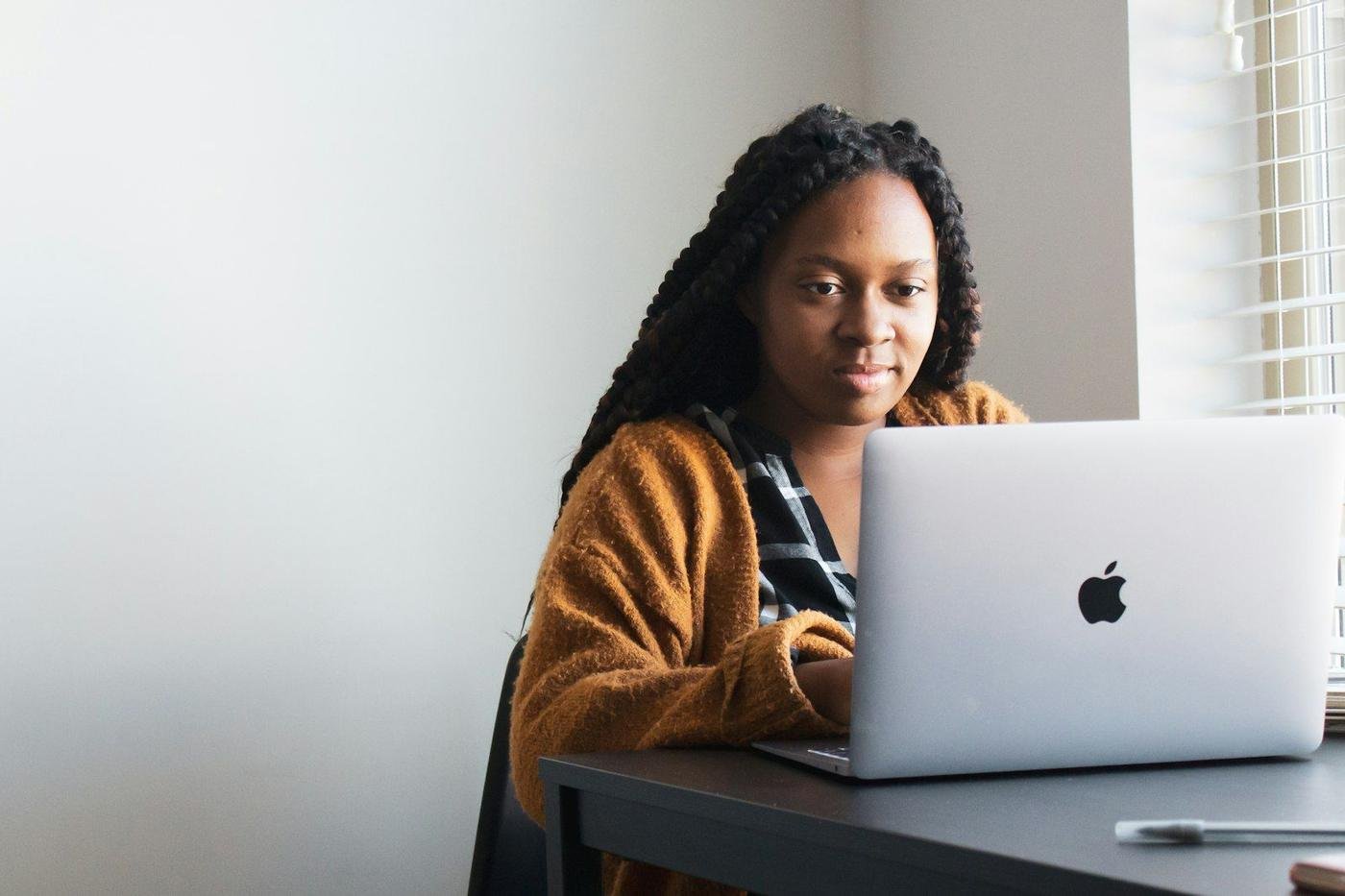 Woman with long braids using a laptop at a desk