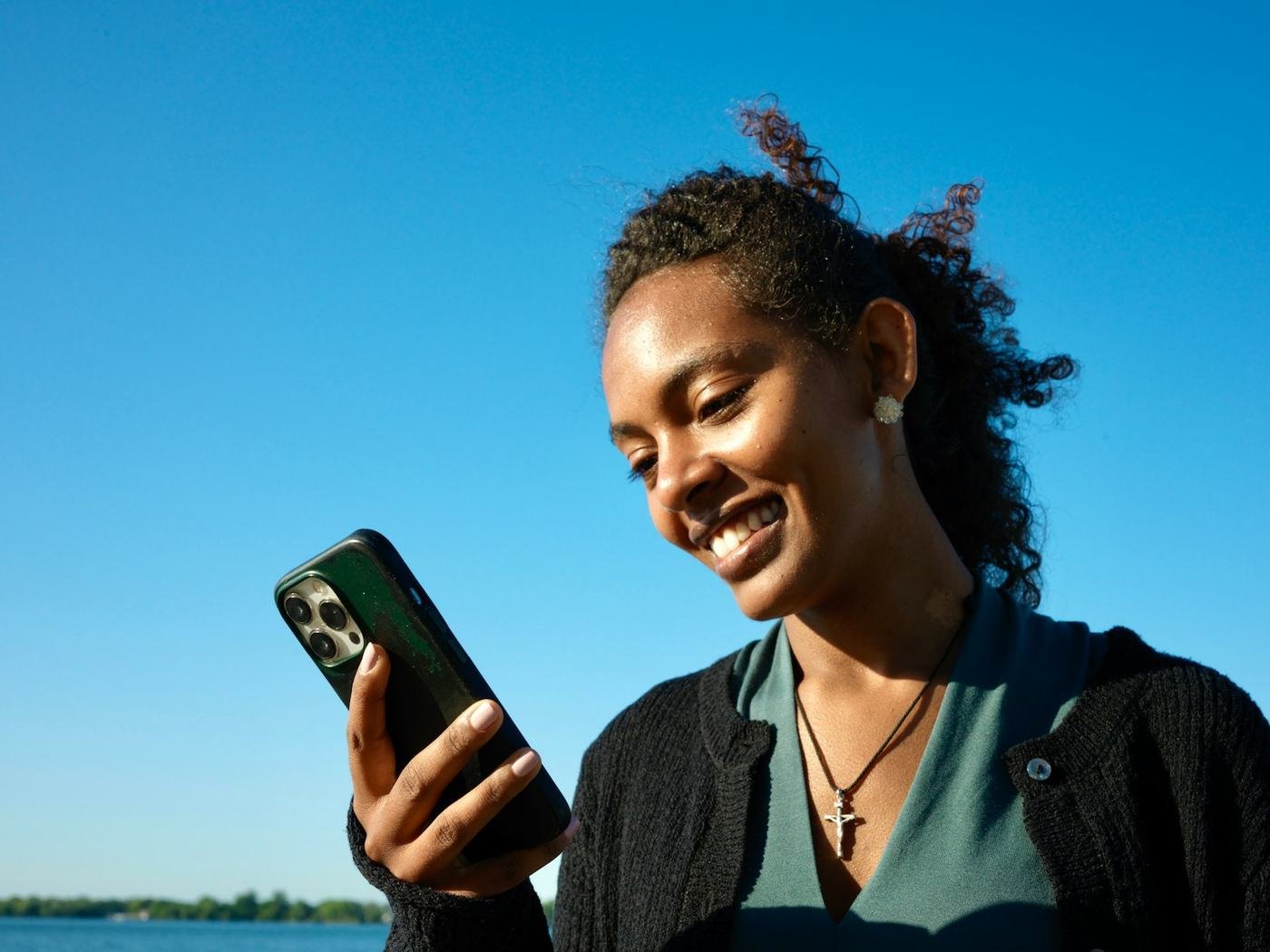 Smiling woman outdoors looking at a smartphone in her hand