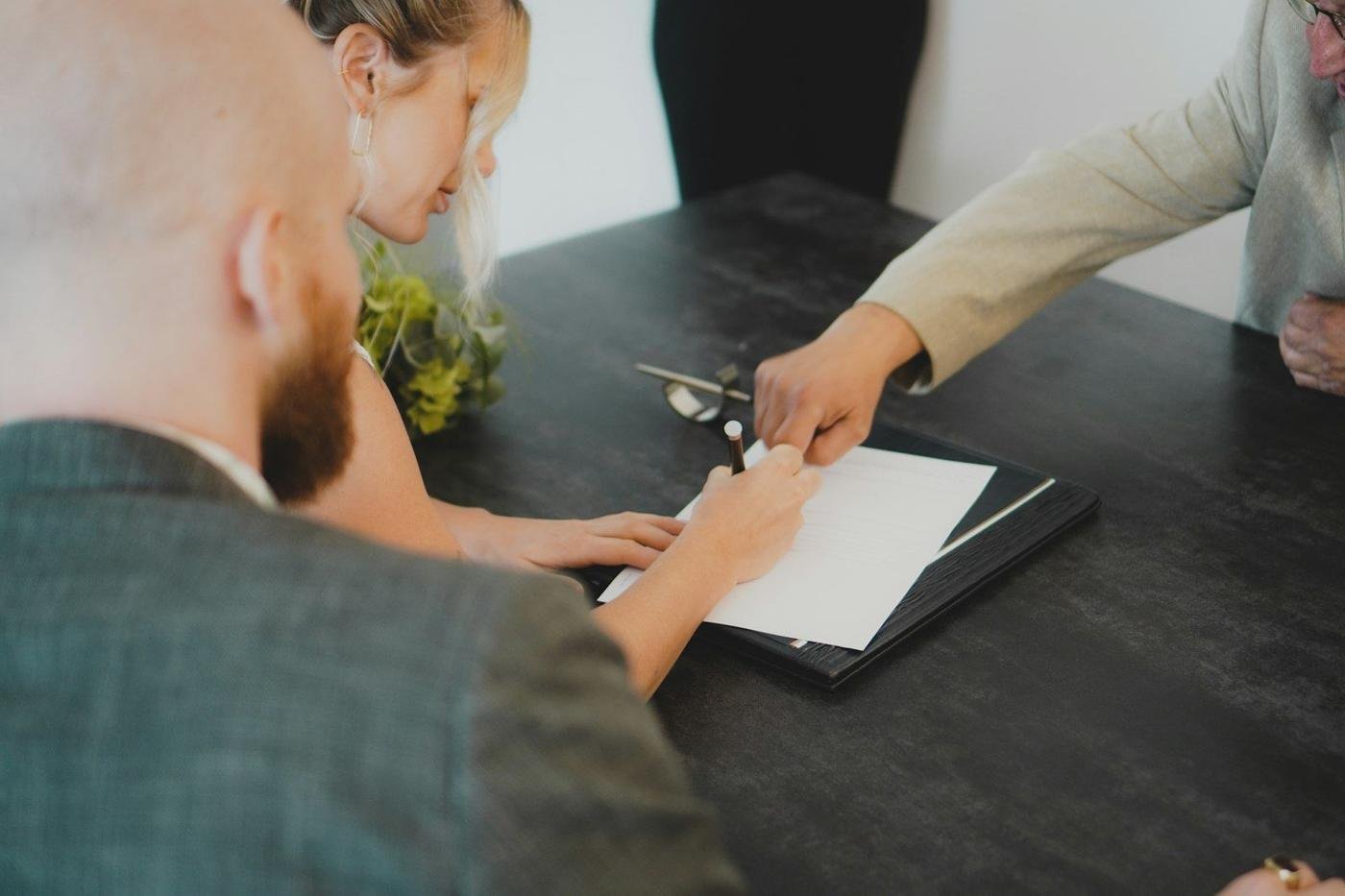 People signing a document at a desk