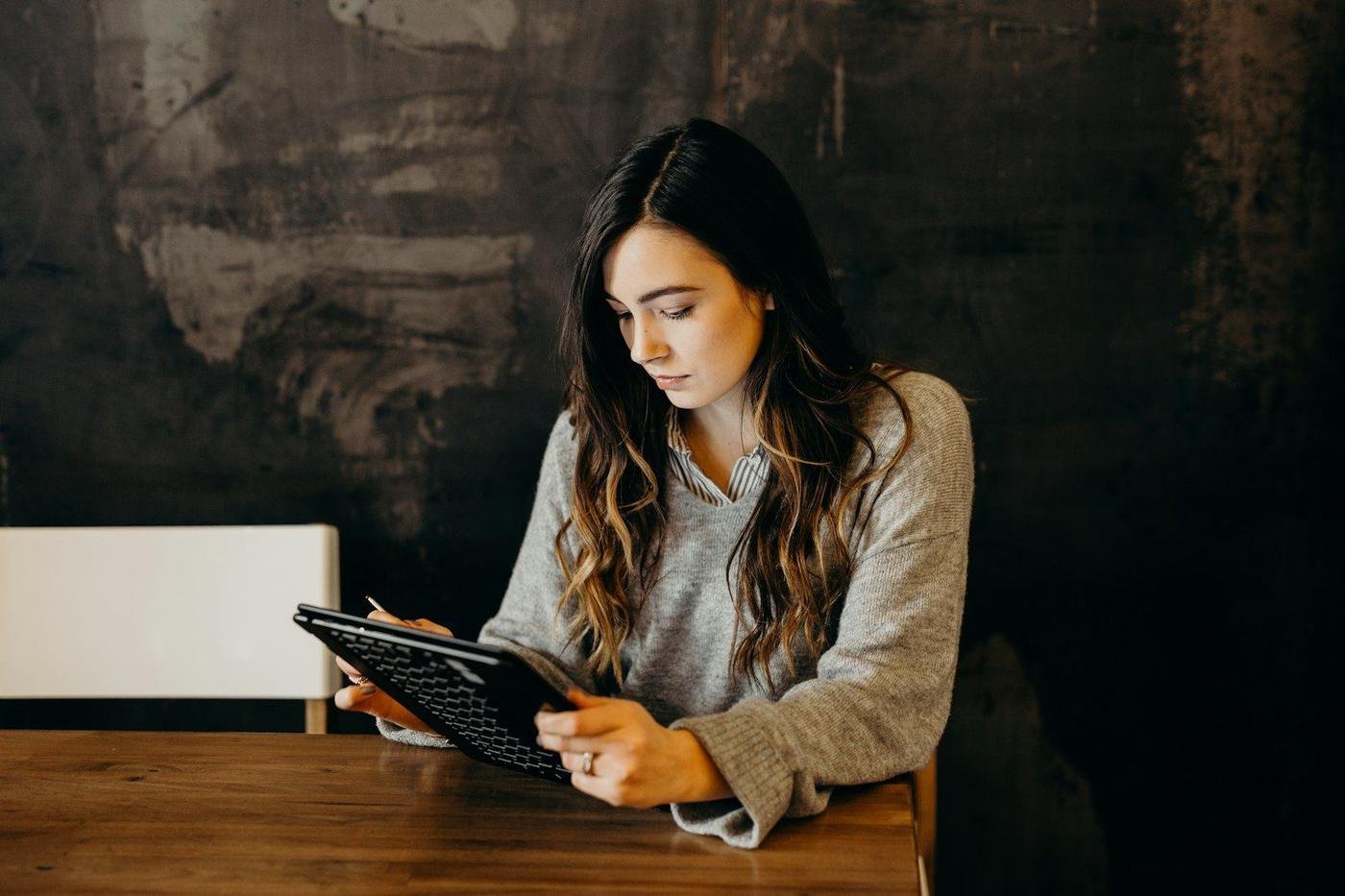 Woman using a tablet at a wooden table