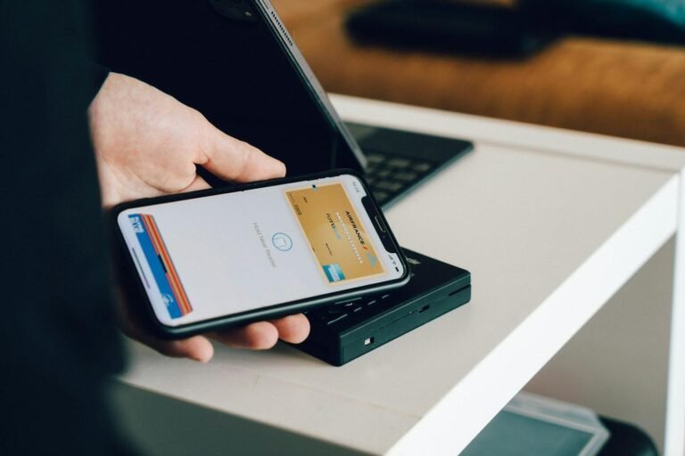 Person holding a smartphone over a card reader for contactless payment